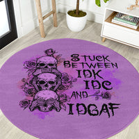 Purple round rug close-up with black skull-and-roses graphic and 'STUCK BETWEEN IDK IDGAF' text