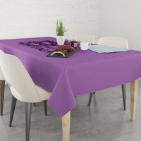Purple tablecloth draped over dining table with neat corner fall.