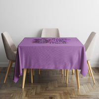 Purple tablecloth on small dining table with four upholstered chairs.