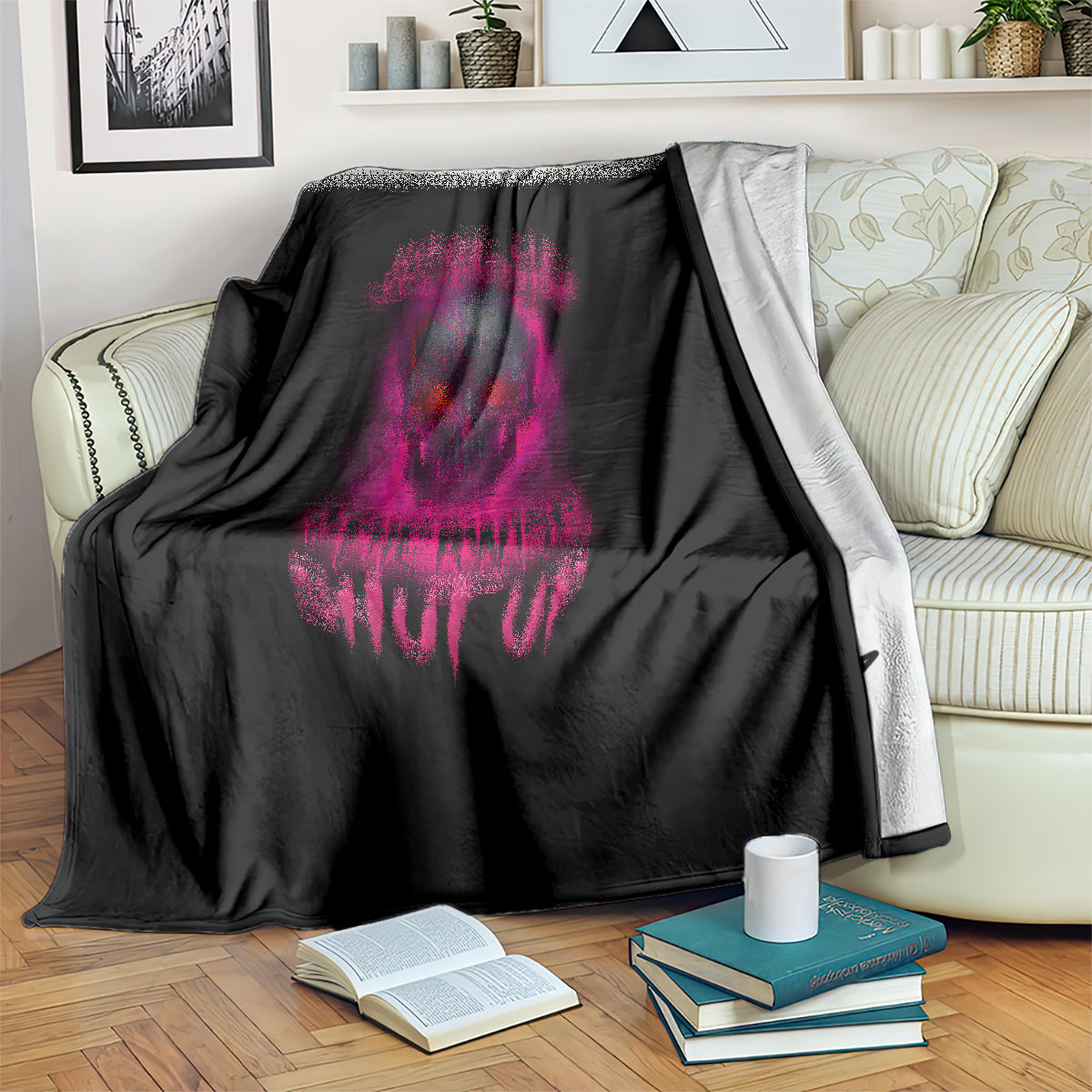 Black blanket with purple skull graphic and text print, draped over sofa arm