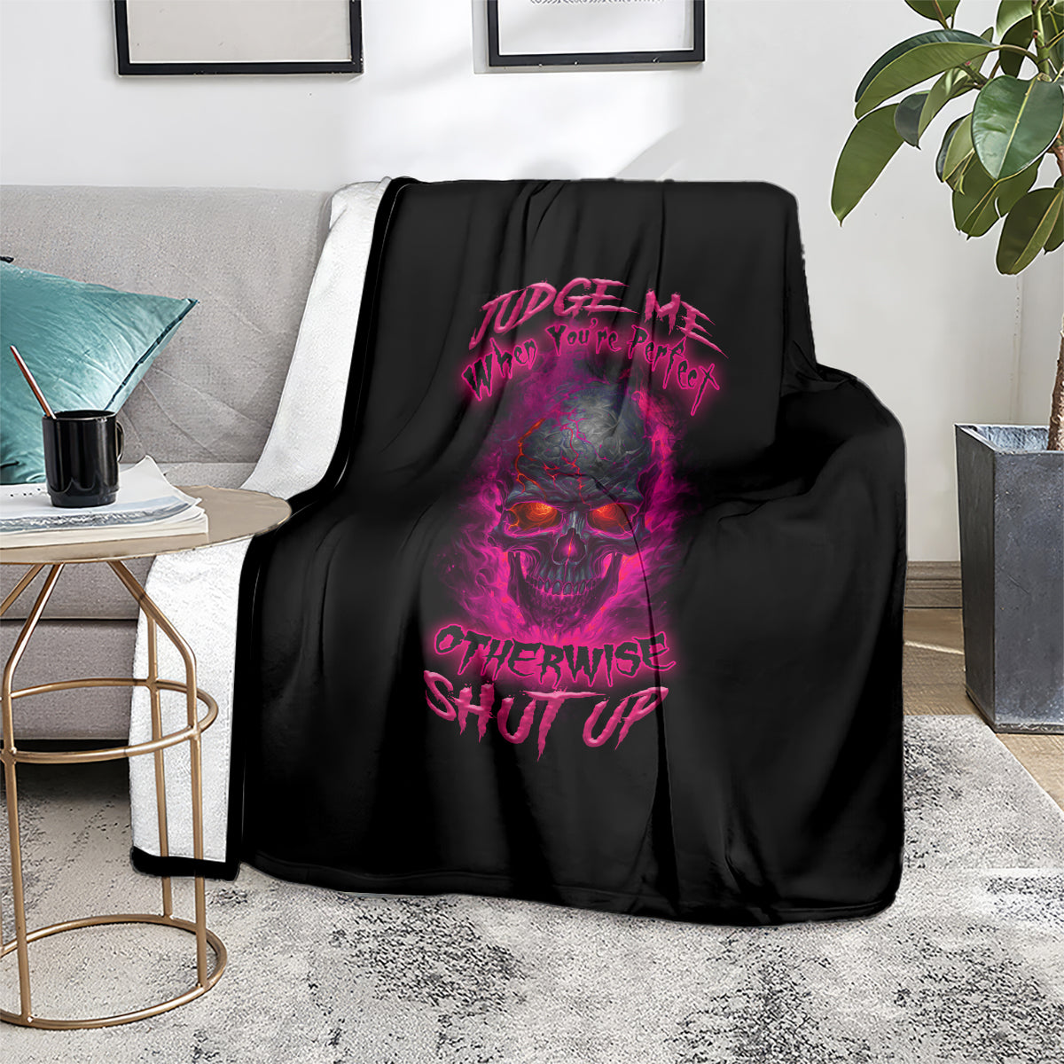 Black throw blanket with purple skull graphic and slogan print, laid on a rug