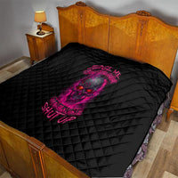 Black quilt with pink skull graphic, quilted diamond texture on a bed
