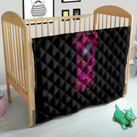 Black quilt with pink skull graphic, diamond quilting laid in a crib