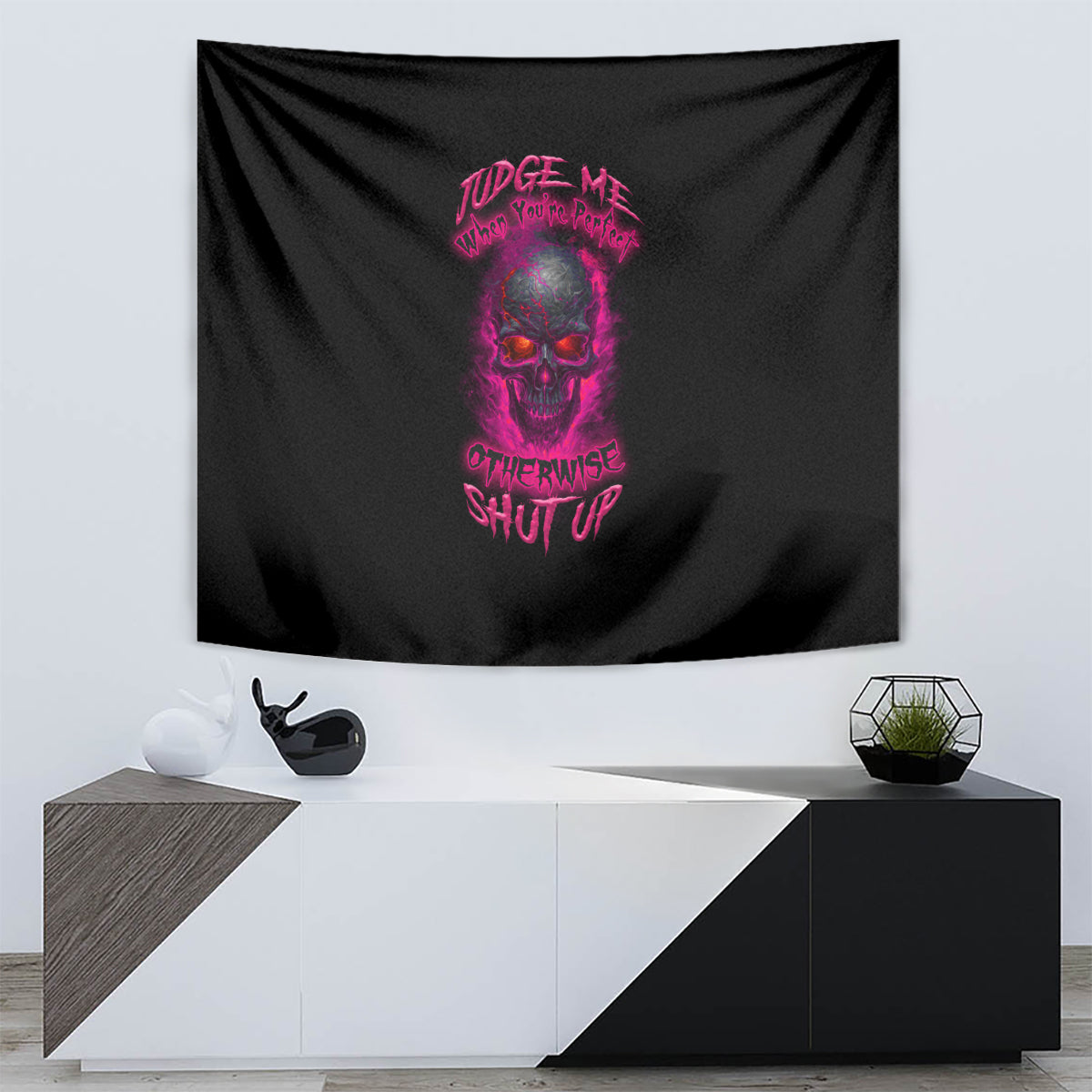 Black tapestry wall hanging with purple skull artwork and slogan text, mounted above a console