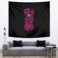 Black tapestry wall hanging with purple skull and slogan text, draped behind a gray couch