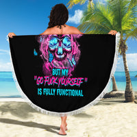Round black beach blanket with fringed edge, neon skull graphic displayed outdoors on sand.