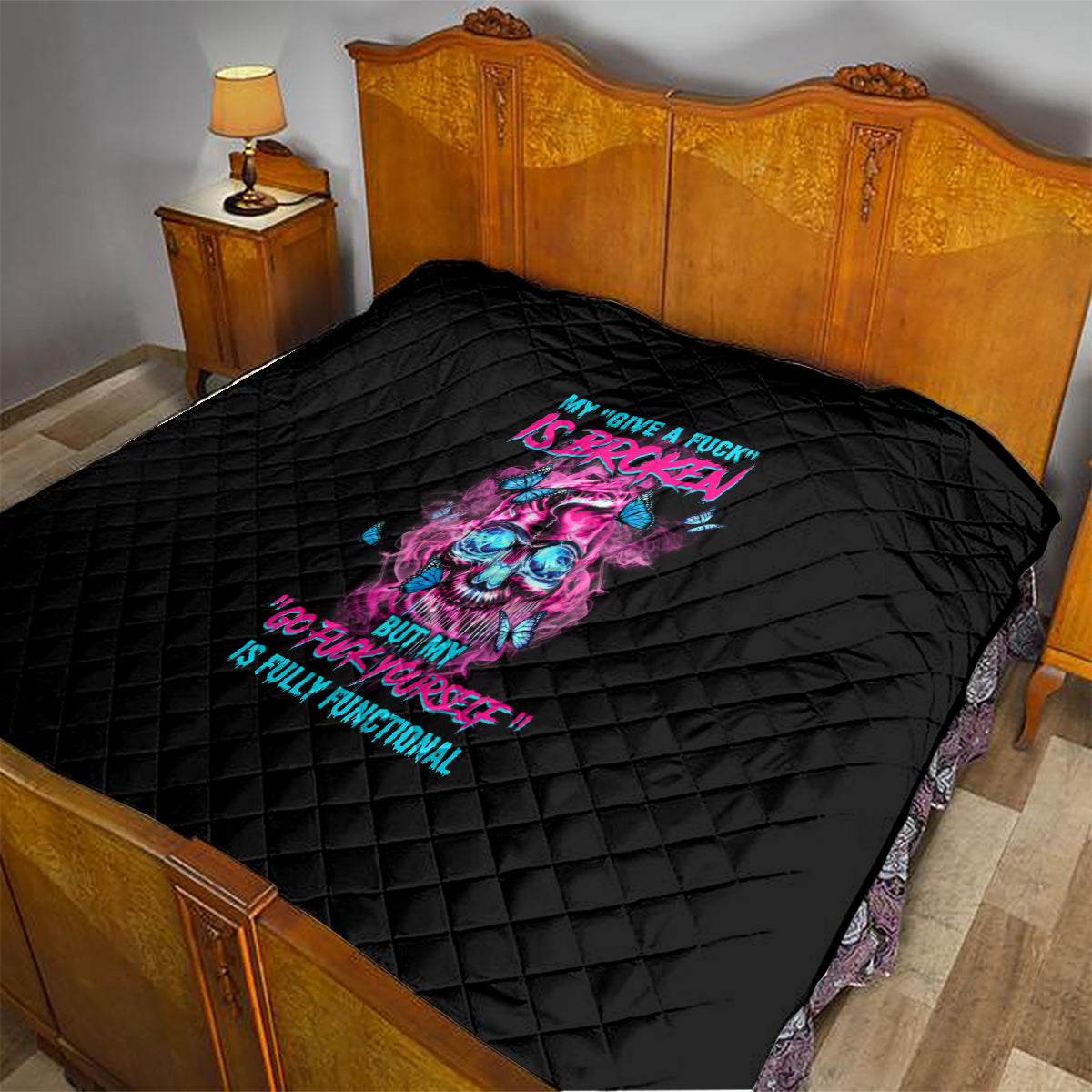 Black quilt laid on bed, neon skull and text graphic with quilted diamond stitching