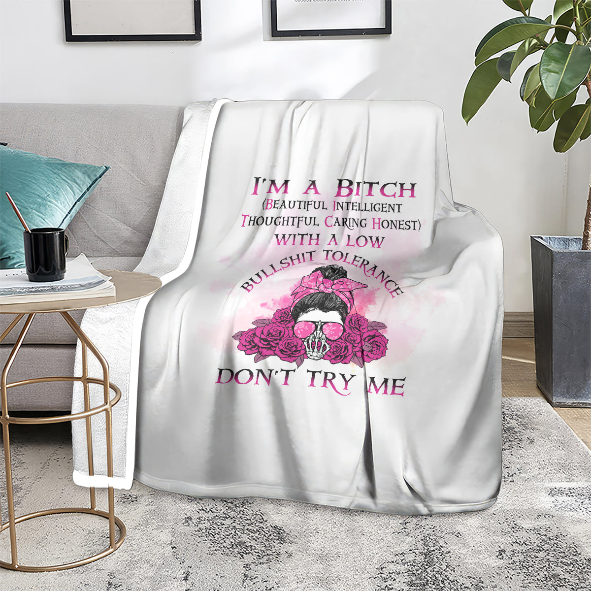 White blanket covering chair with pink floral skull graphic and purple text, centered on couch.