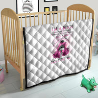 White quilt with diamond stitching and pink rose character and quote on a crib.