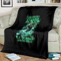 Black blanket with teal-green reaper skull print, spread across a couch