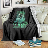 Black blanket with green skull reaper design, laid over a striped sofa