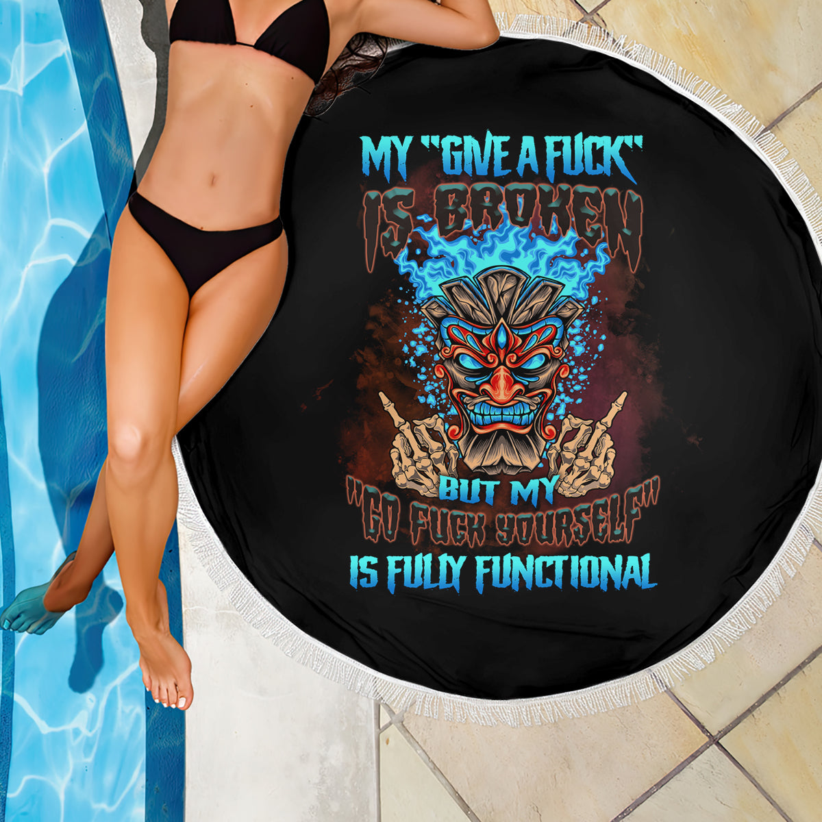 Black round beach blanket with white fringed edge and colorful tiki skull graphic
