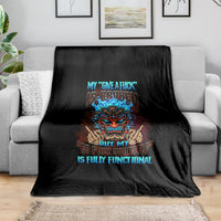 Black skull blanket with colorful tiki face graphic and blue text, draped on a sofa