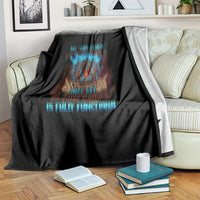 Black skull blanket with blue and orange tiki skull artwork and text, over a couch