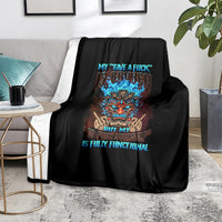 Black skull blanket with colorful tiki skull graphic and blue text, laid on a sofa
