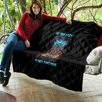 Black quilt with diamond stitching and colorful tiki skull graphic, laid across sofa