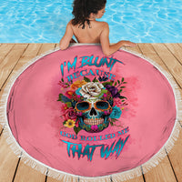 Round pink beach blanket with fringe edge, skull and flowers printed on center