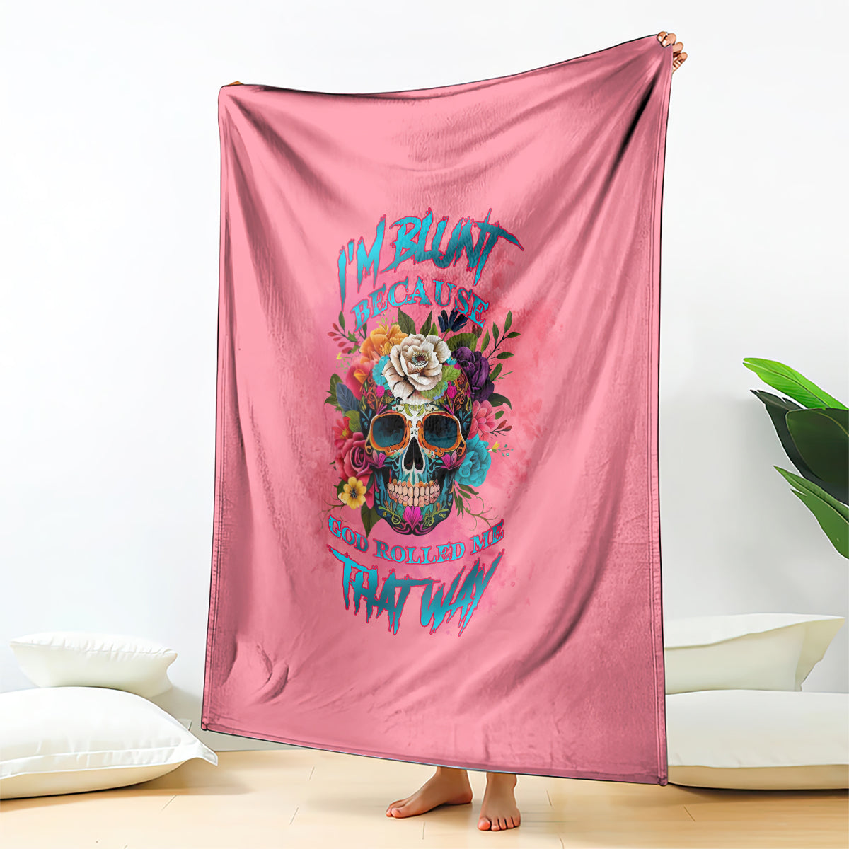 Pink blanket with skull artwork and text, hung vertically indoors