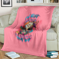 Pink blanket with multicolor skull graphic and text, spread over a couch