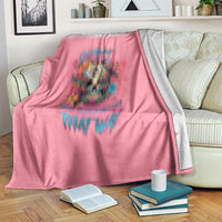 Pink throw blanket with skull design and text, draped over a sofa arm with books