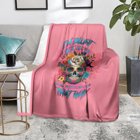 Pink blanket with colorful skull and text, laid over a gray chair