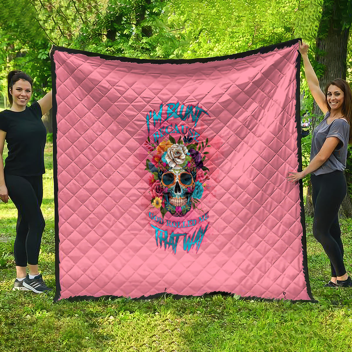 Pink quilt with diamond stitching and colorful skull floral graphic in the center