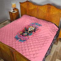 Pink quilt on bed with centered skull floral graphic and diamond stitched texture