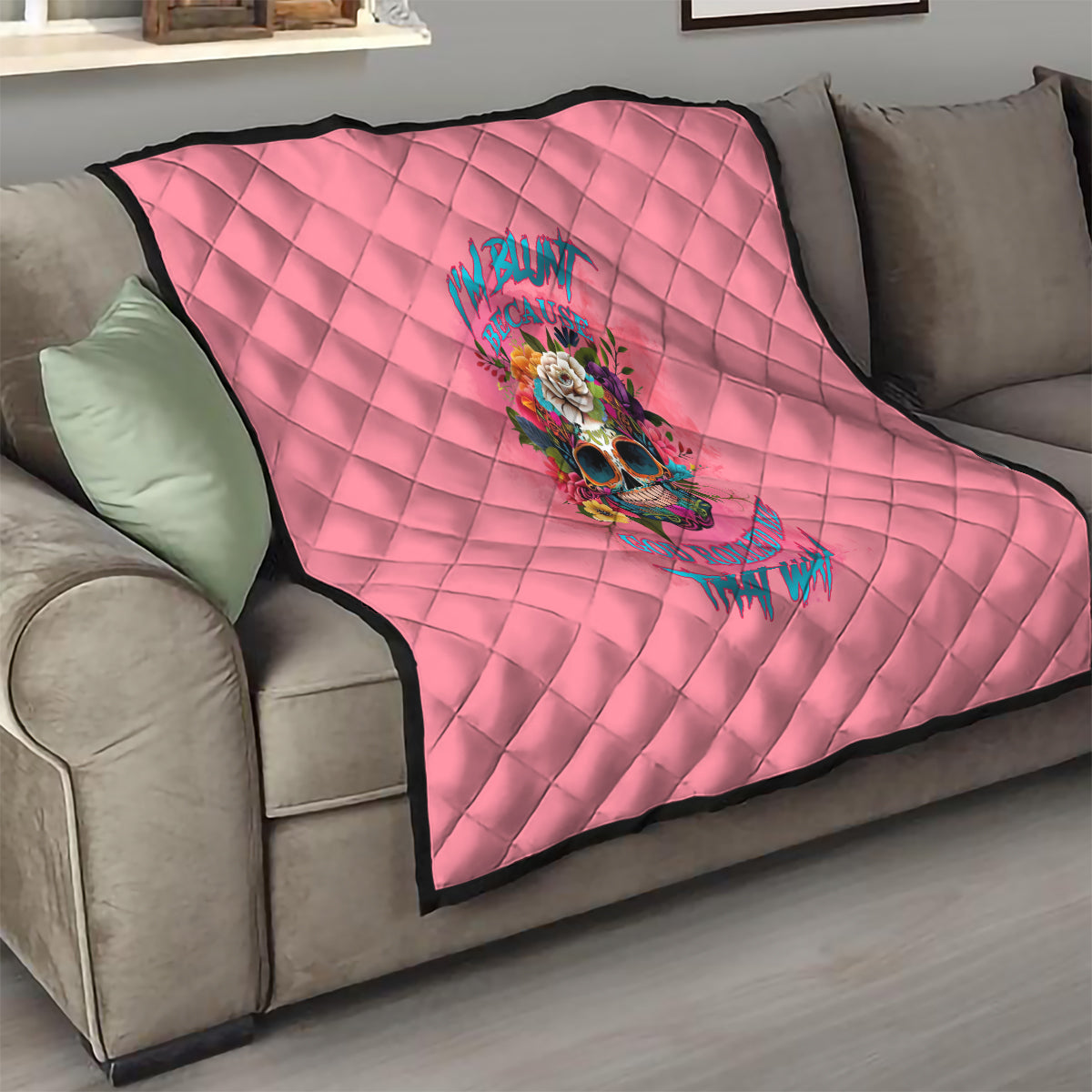 Pink quilt on sofa with diamond pattern and centered colorful skull floral artwork