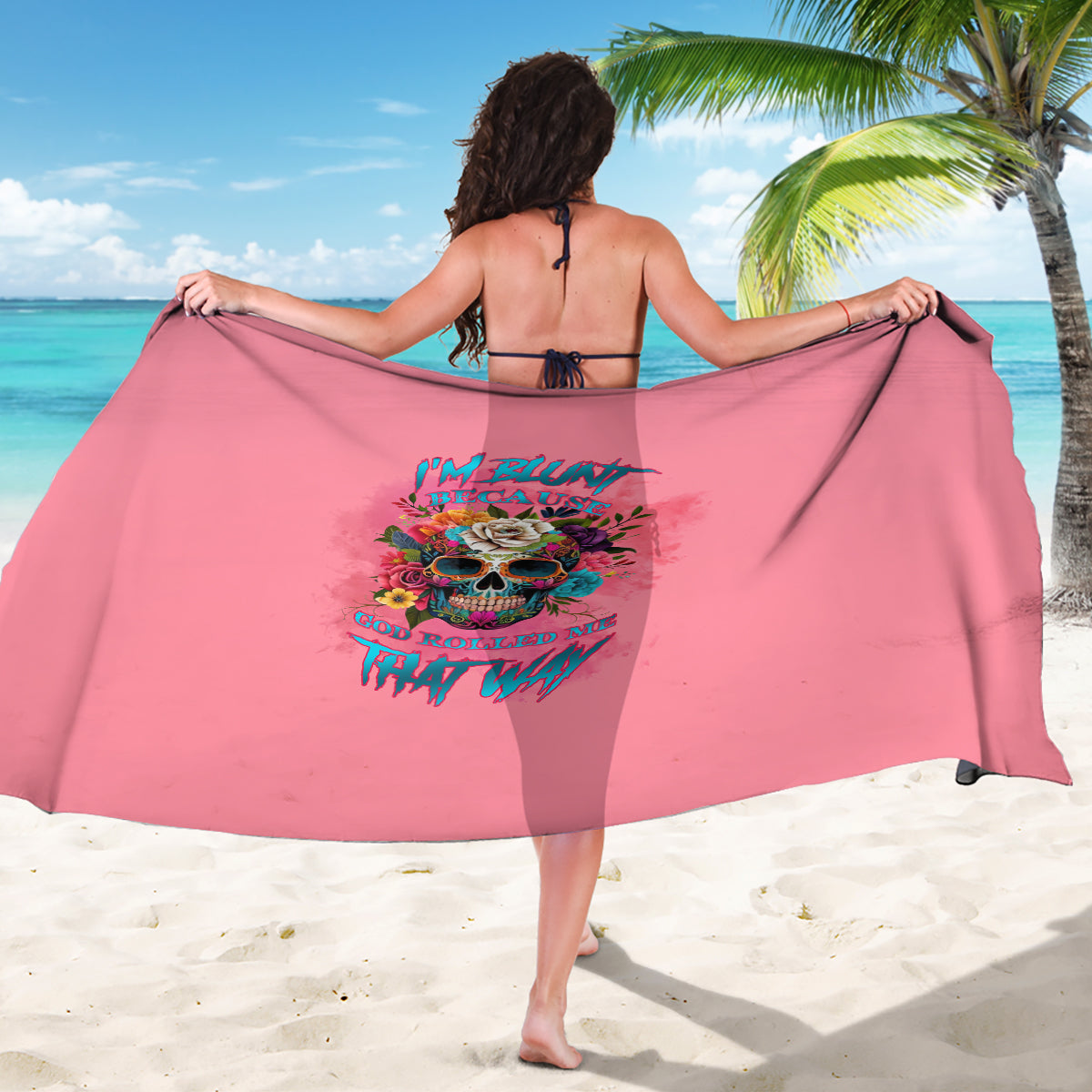 Pink sarong with colorful skull graphic and bold text, draped on model