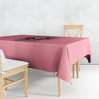 Pink tablecloth with colorful floral quote graphic, draped over a dining table corner.