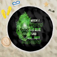 Round black beach blanket with neon-green skull face graphic and white fringed edge