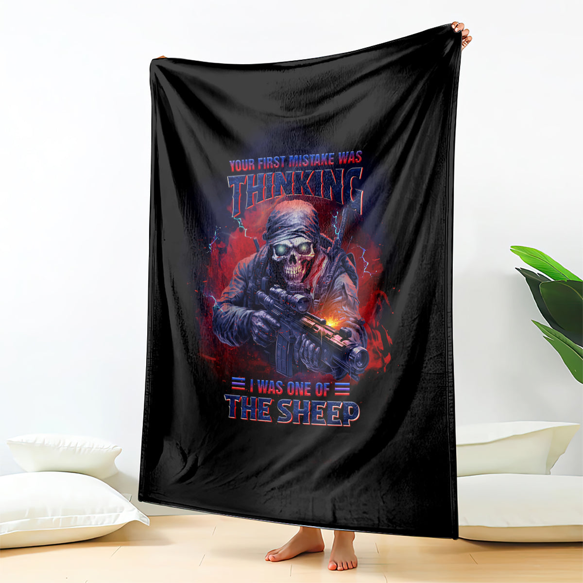 Black graphic throw blanket with skull-and-rifle artwork and red-blue slogan text