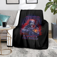 Black graphic blanket with skull holding rifle and red-blue text, folded on couch