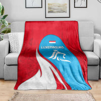 Luxembourg flag blanket draped over gray sofa, red white blue with lion crest