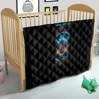 Black quilt with diamond quilting draped over crib, showing colorful tiki skull graphic