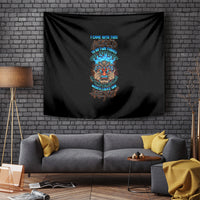 Black skull tiki tapestry with multicolor text graphic, hung on brick wall