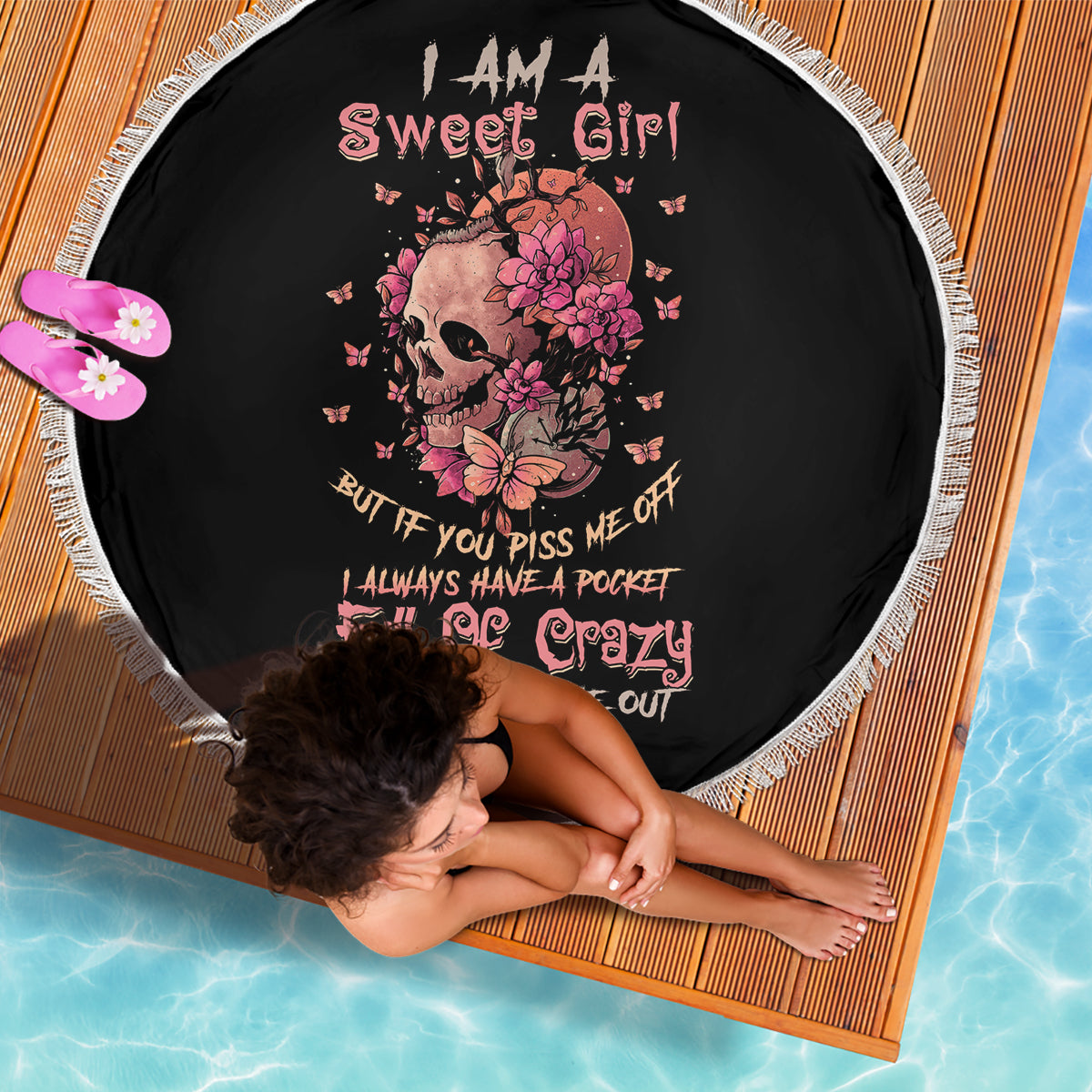 Black round beach blanket with pink floral skull graphic and white fringe edging
