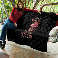 Black quilt blanket with diamond stitching and pink flower skull print, folded on a sofa