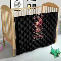 Black quilt blanket with diamond stitching and pink flower skull graphic on a crib
