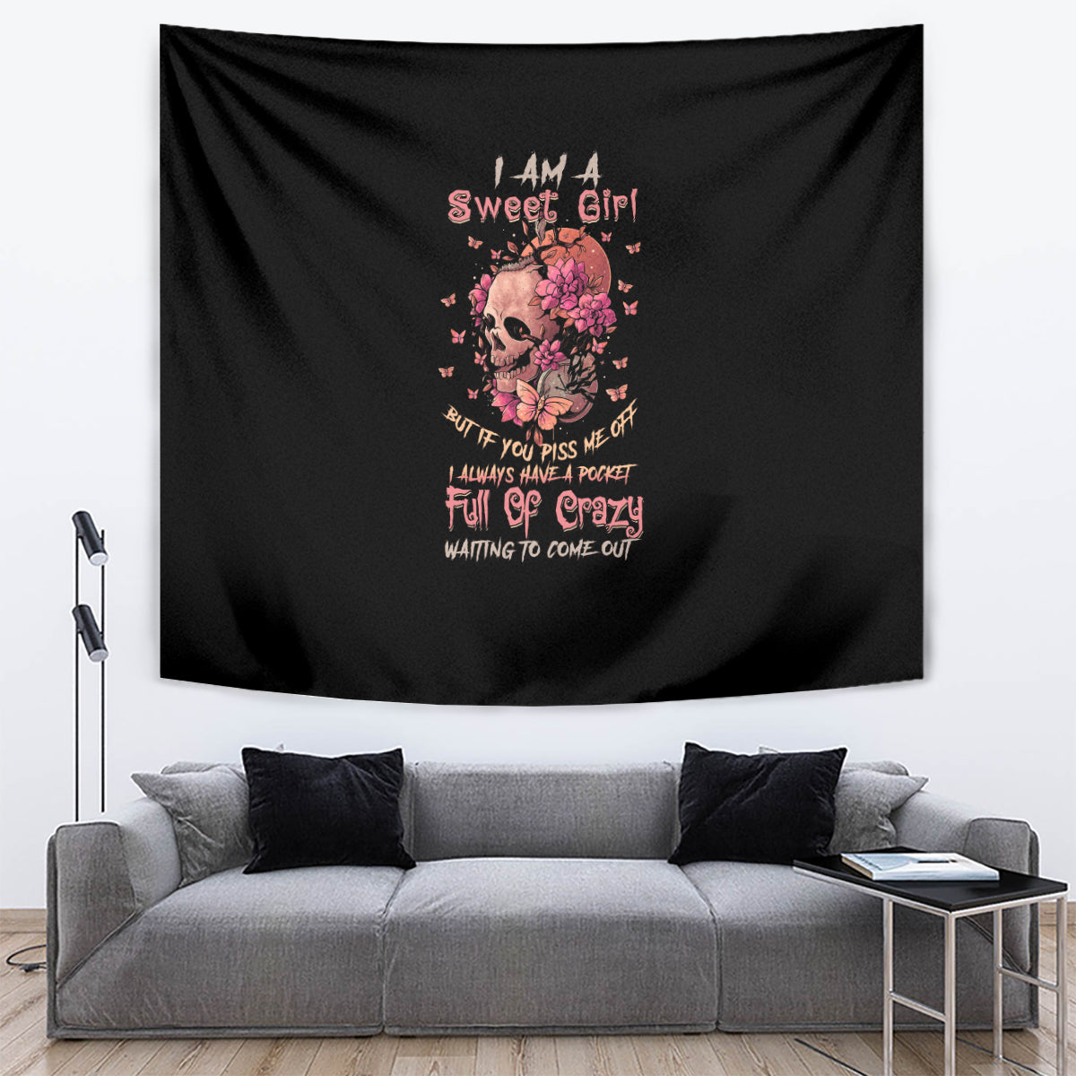 Black tapestry hanging above sofa, with floral skull and multicolor quote