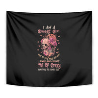 Black tapestry close-up: floral skull portrait with pink flower details and text