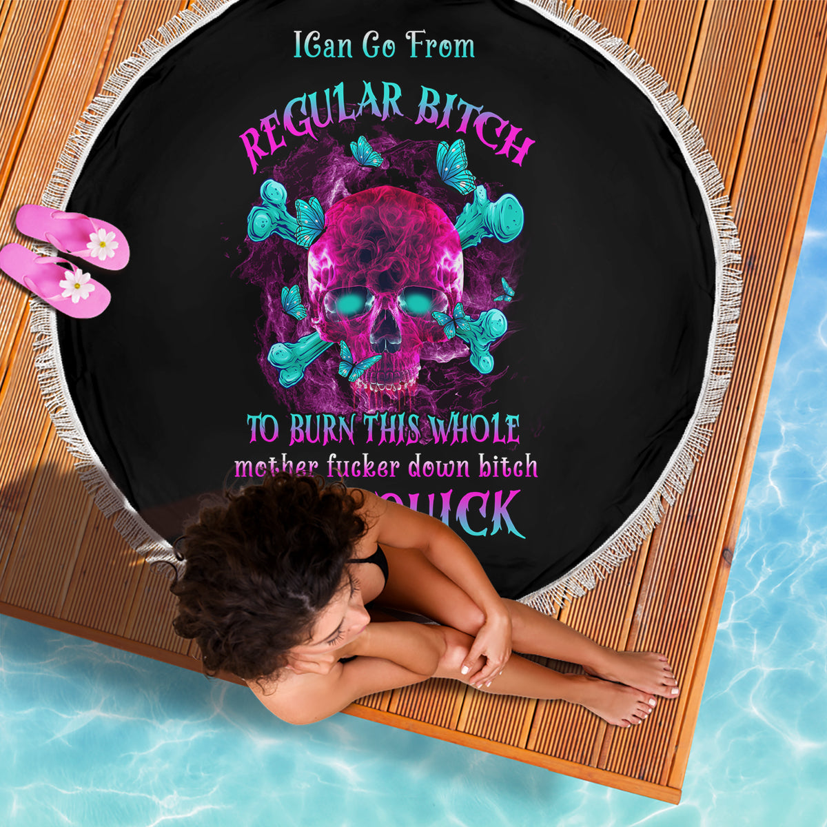 Round black beach blanket with neon skull graphic, fringe edge; dog lying on it