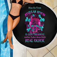 Round black beach blanket with neon skull graphic, fringe edge; person in black bikini