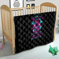 Black quilt with diamond stitching and colorful skull graphic, placed in a baby play area