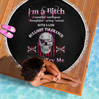 Black round beach blanket with fringe edge and skull with crossed bones graphic in pink