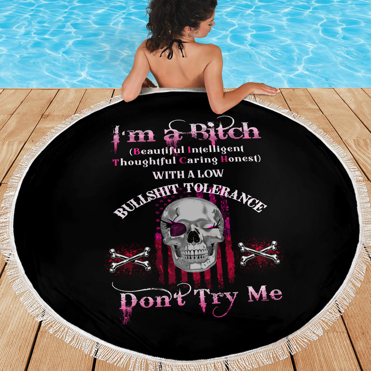 Round black beach blanket with fringe border, skull and crossed bones graphic centered