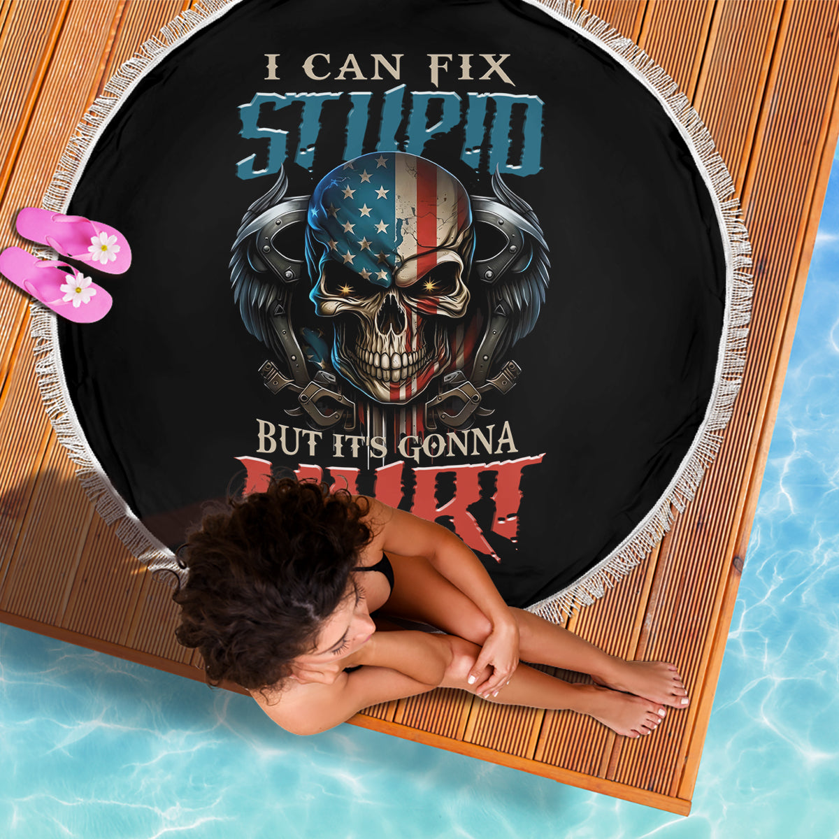 Round black beach blanket with bold skull and wings graphic, fringed edge
