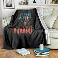 Black blanket with distressed skull print and blue/red lettering, draped over couch