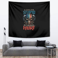 Black tapestry with skull and slogan, hanging on the wall above a gray sectional.