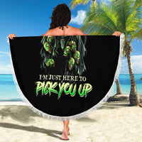 Round black beach blanket with green skull print and white fringed edge, spread out